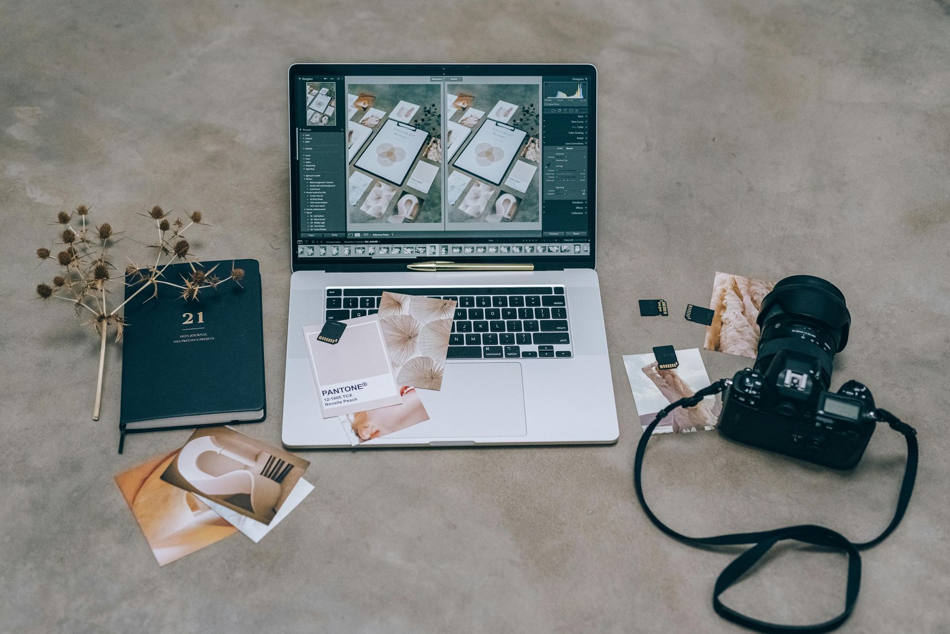 Flat lay of laptop, camera, notebook, flowers, and coffee on a beige desk