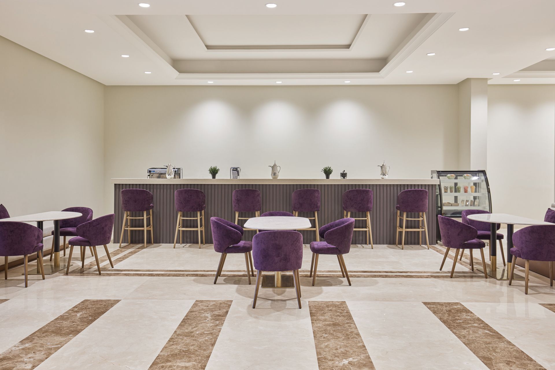 Elegant hotel lounge with purple chairs, bar counter, and marble-patterned floor