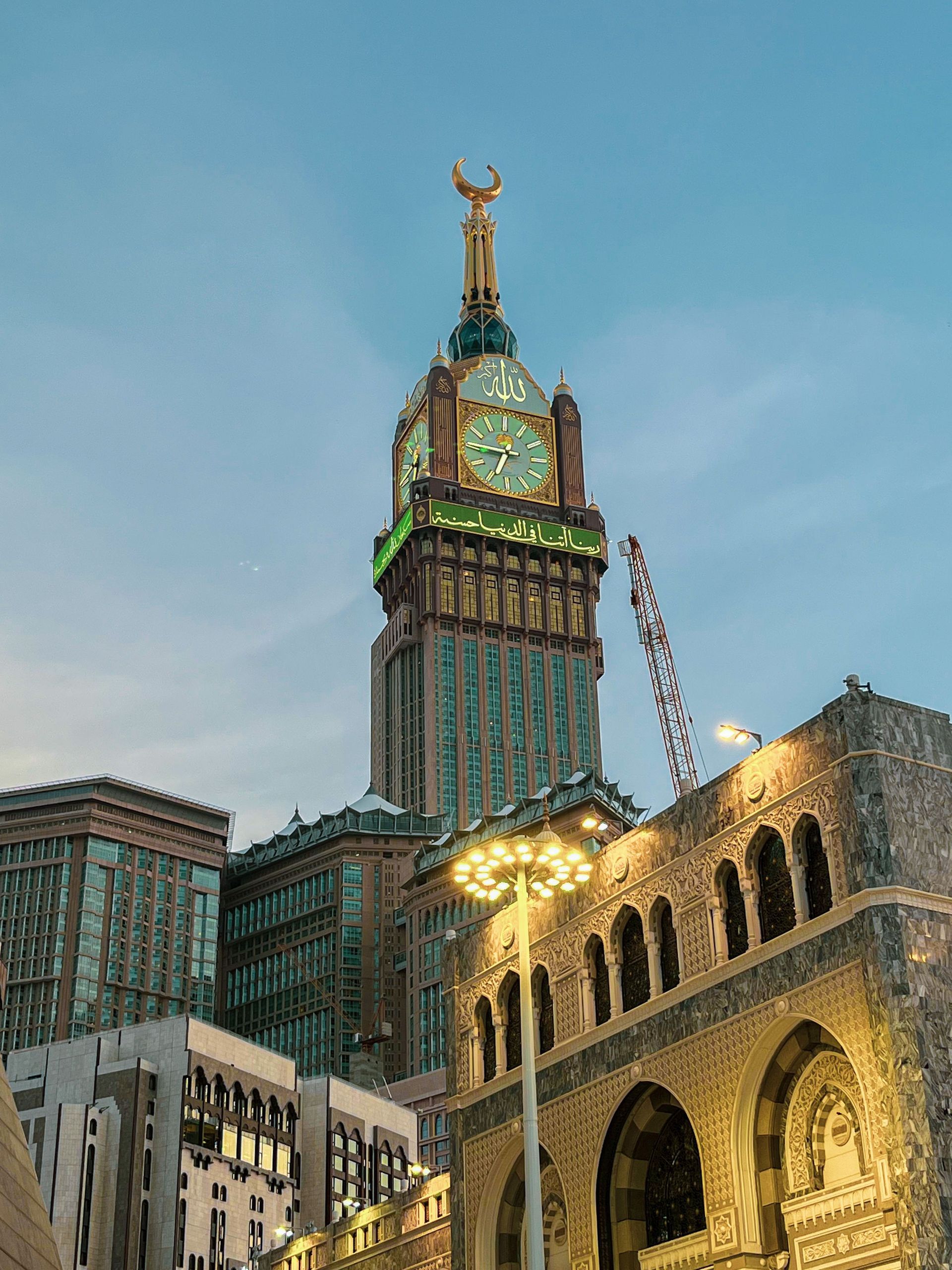 Clock tower with a golden statue atop a tall building at dusk beside an arched stone facade