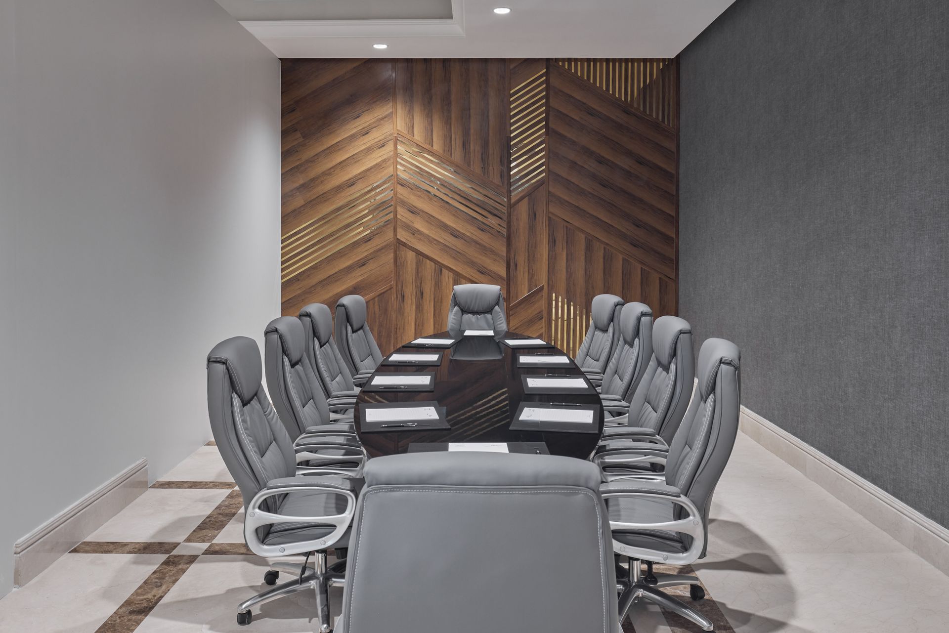 Modern conference room with gray chairs around a long table and a wood accent wall