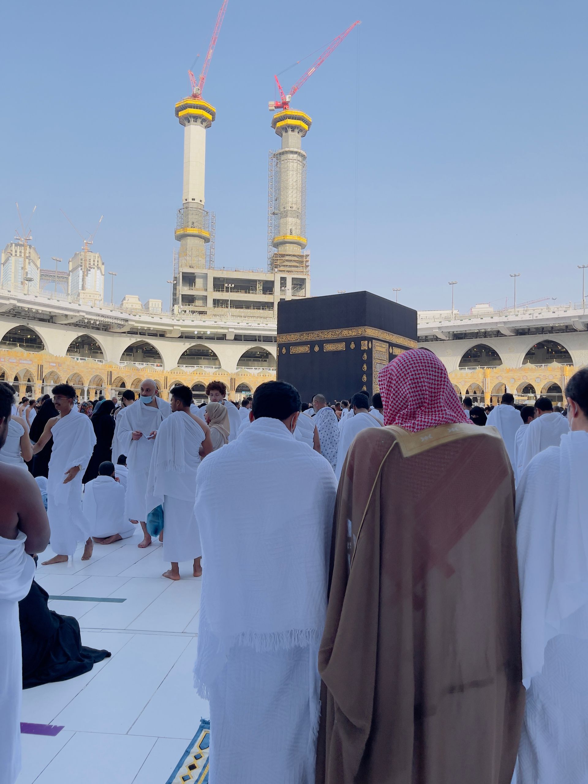 Pilgrims in white garments circling the Kaaba at the Grand Mosque in Mecca, with minarets in the background