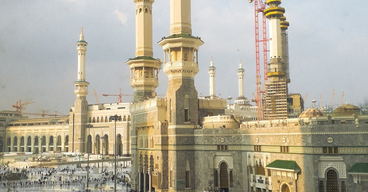 Grand mosque with tall minarets and cranes under construction beside the Kaaba in Mecca