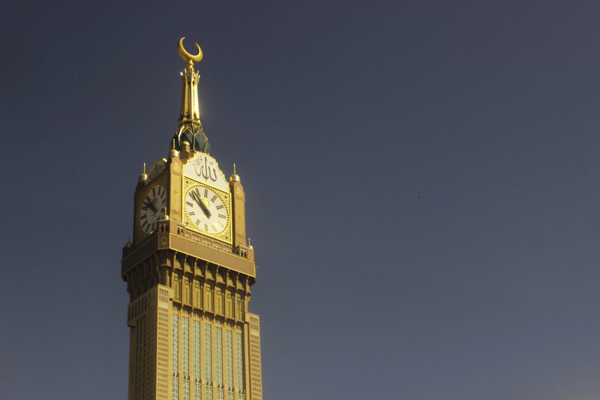 Clock tower of the Abraj Al Bait with gold accents against a clear sky