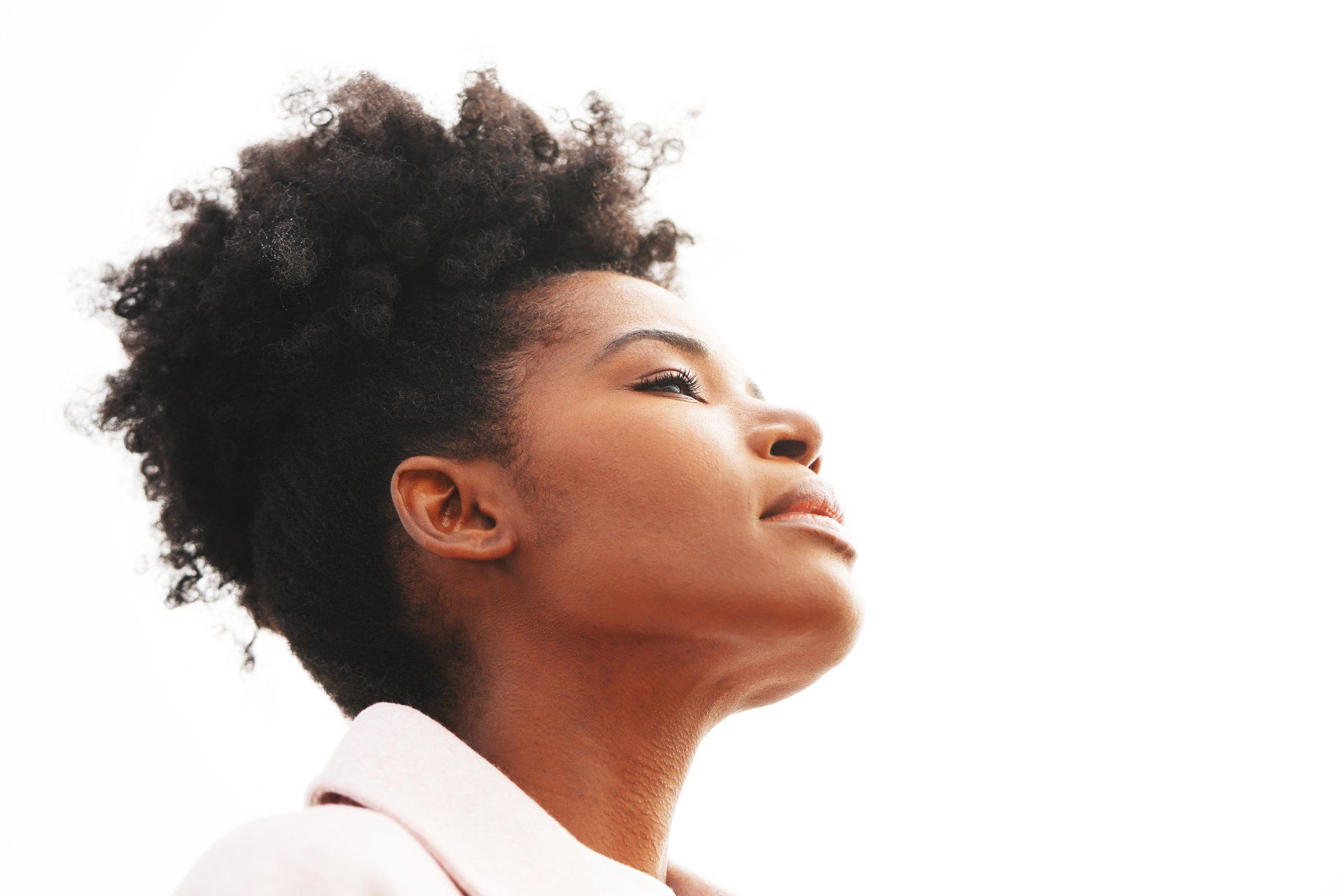 A woman with curly hair is looking up at the sky.