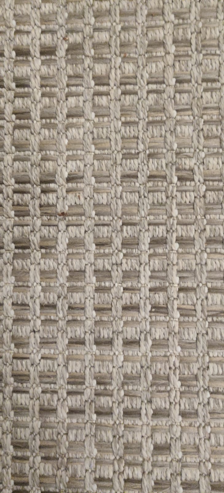 Detailopname van een geweven, gestructureerde stof in beige en grijze tinten, met een geometrisch patroon.