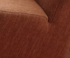Detailopname van een bruine corduroy armleuning van een bank met een lichtere stof aan de bovenrand.