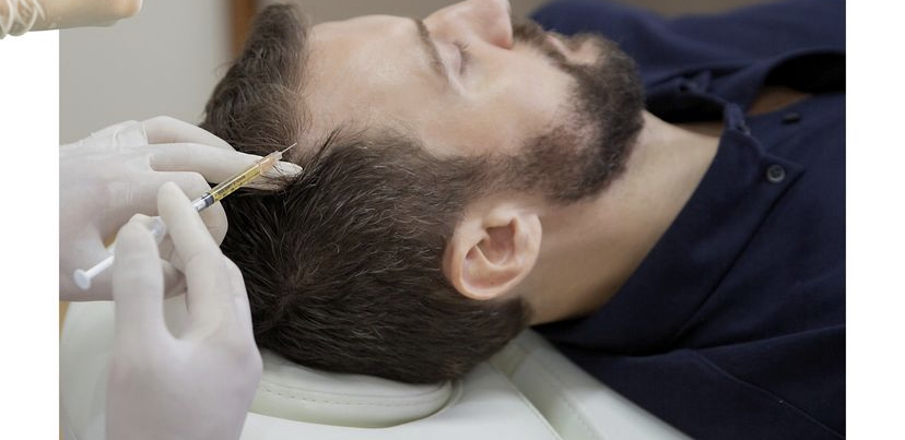 Person receiving a scalp injection; a healthcare worker with gloved hands.