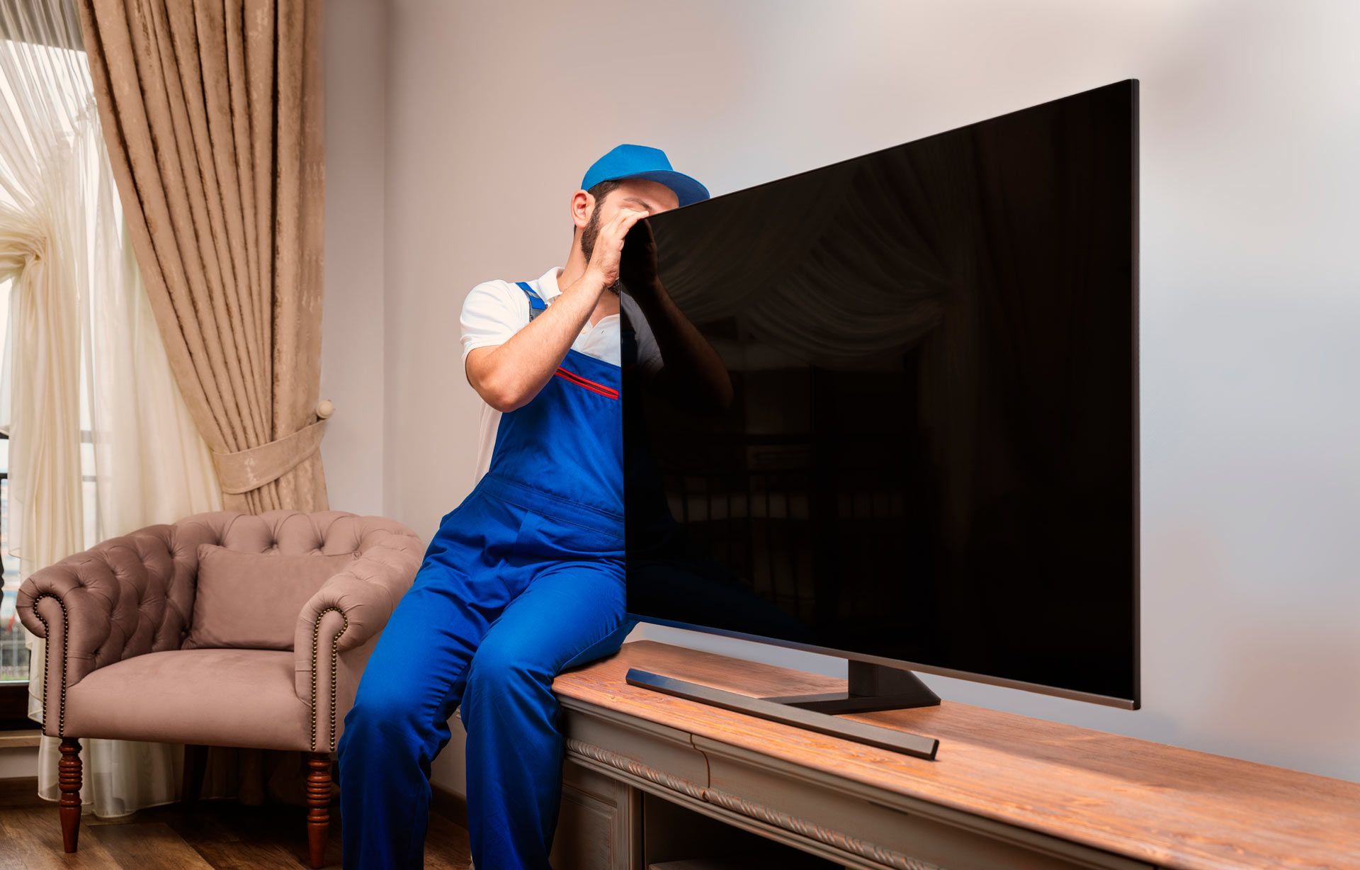 A man is sitting on a table next to a television.