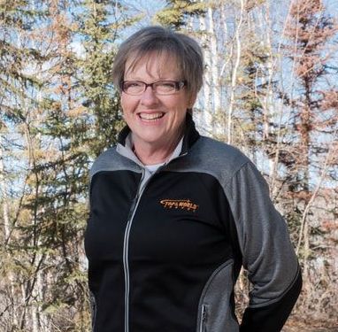 women smiling before camera A woman wearing glasses and a black and grey jacket with the word company on it