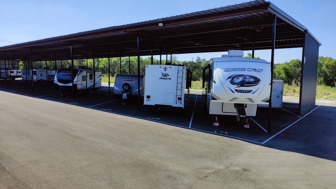 Covered RV storage lot with various RVs parked under a metal canopy.