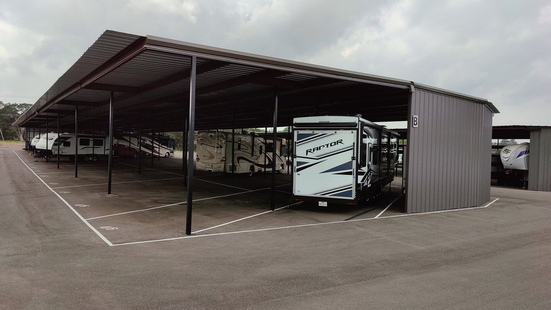 RVs parked under a large metal carport at a storage facility.