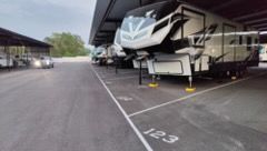 RV trailers parked in covered storage bays with numbered spaces on a paved lot