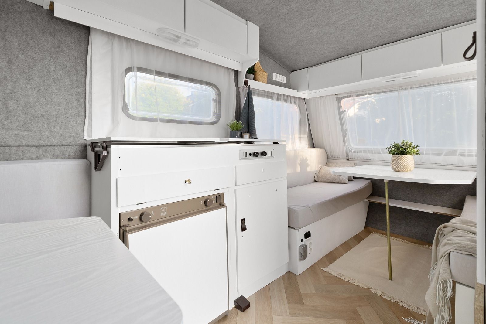 Interior of a white camper van with a kitchen area, seating, and a table.