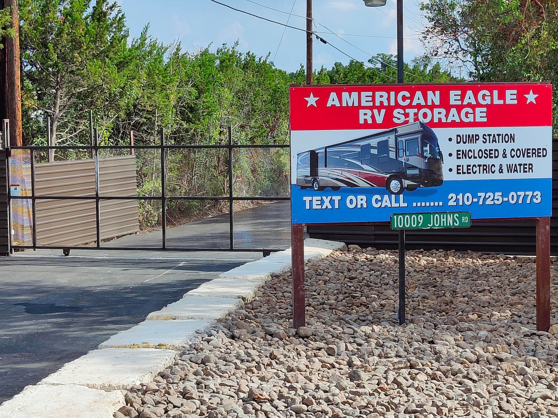American Eagle RV Storage sign beside a gated gravel lot and driveway