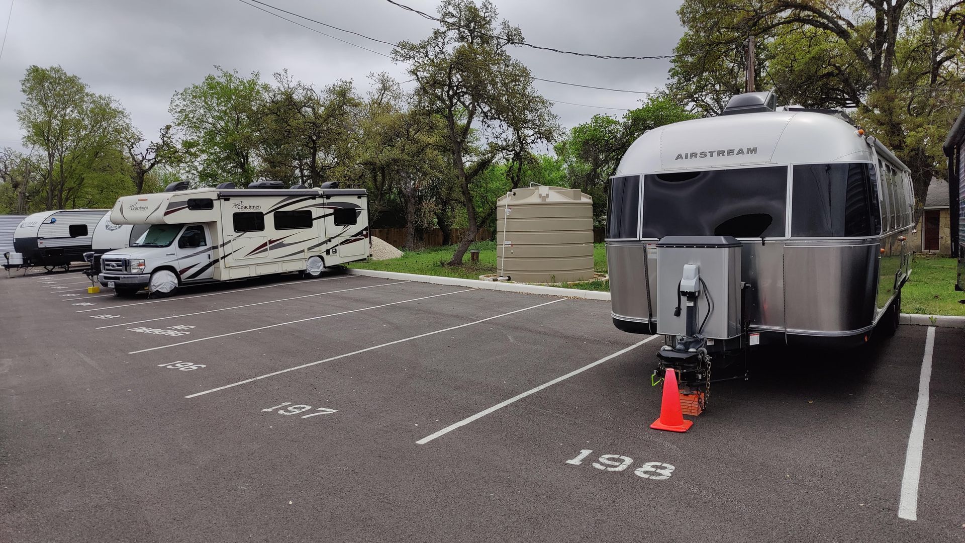 RV parking lot with two parked trailers, numbered spaces, and an orange traffic cone by a silver Airstream.