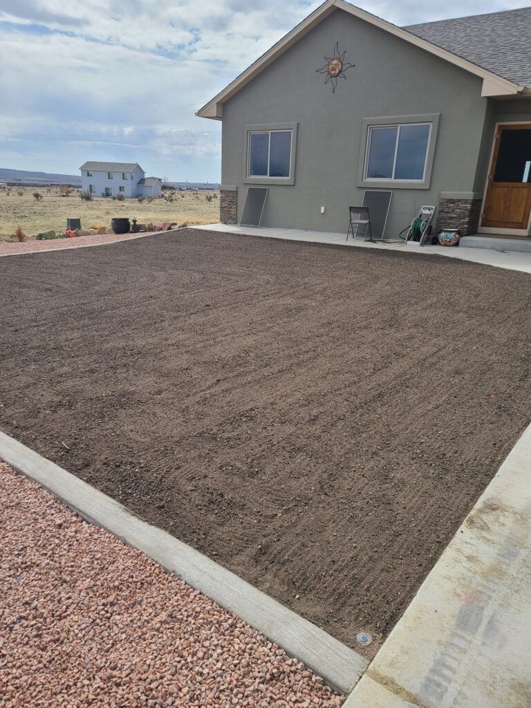 Freshly landscaped gravel yard beside a gray house with concrete edging