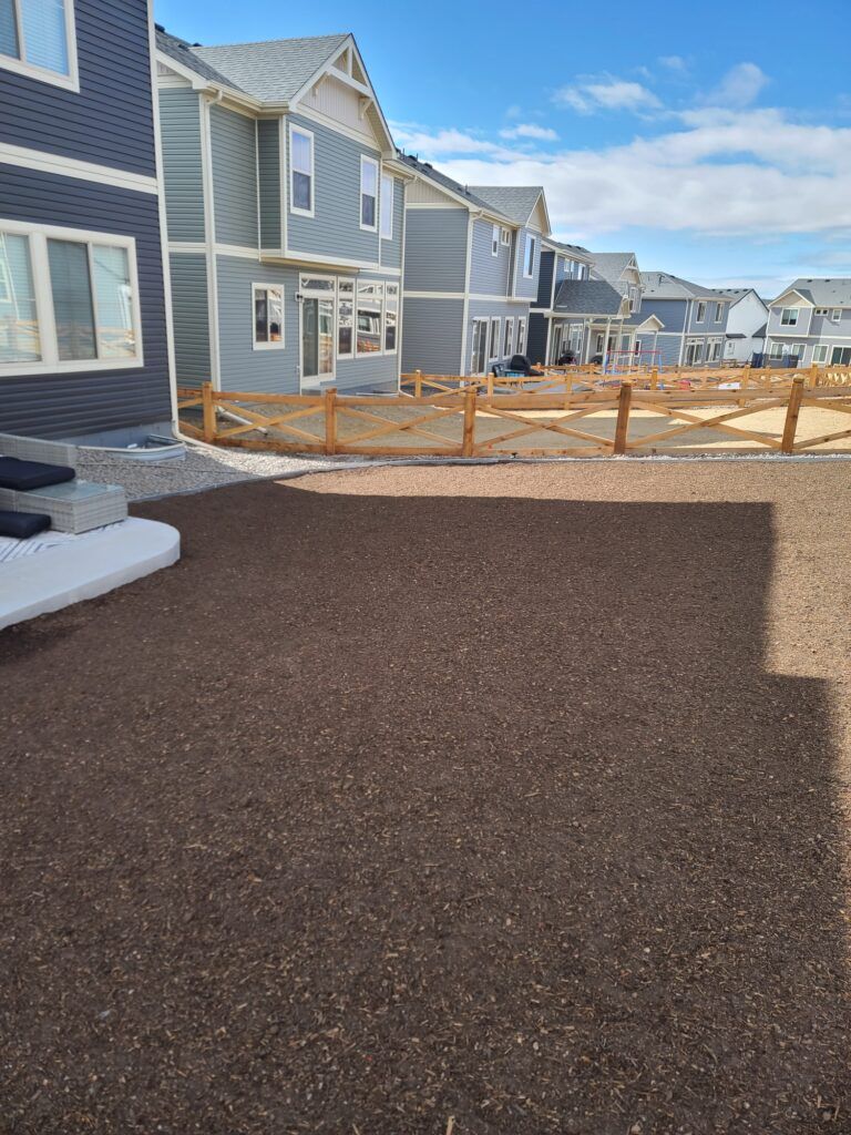 New townhouses with fresh paved driveway and orange safety fencing under a blue sky