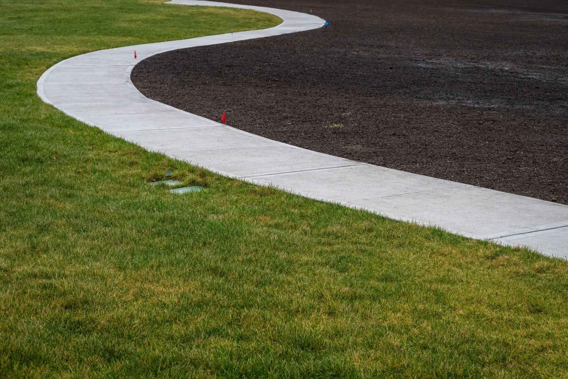 Curved white track edge beside green grass and dark asphalt on a racetrack