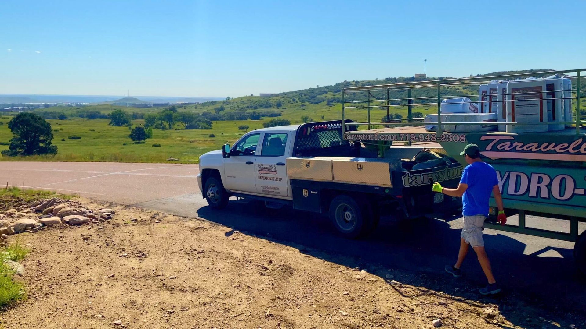 White pickup truck with trailer on a dirt road overlooking a green rural valley White pickup truck with trailer on a dirt road overlooking a green rural valley