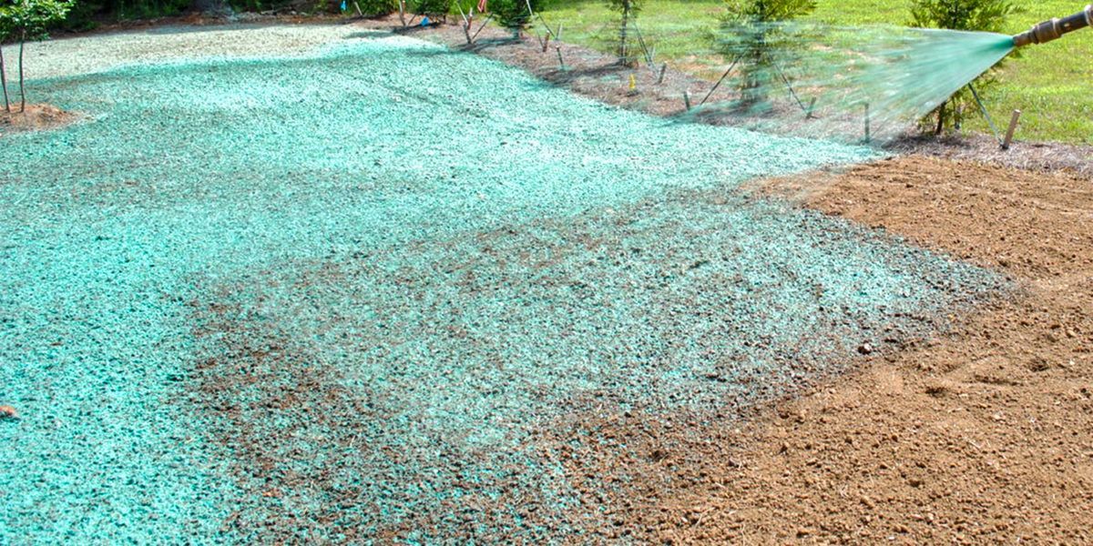 Large turquoise water spill spreading across a tan dirt path in an outdoor area Large turquoise water spill spreading across a tan dirt path in an outdoor area