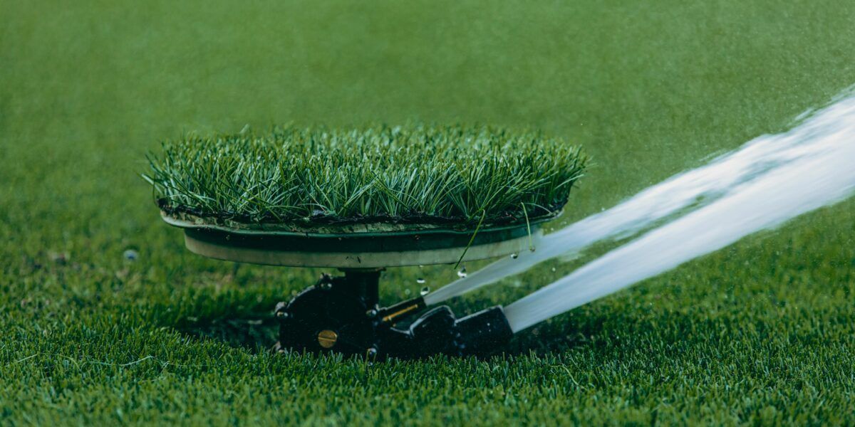 A lawn sprinkler sprays water over a patch of green grass.