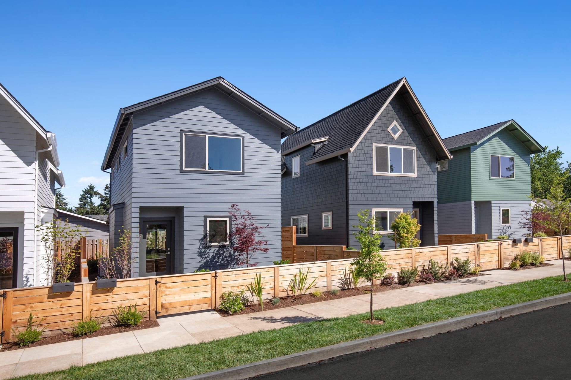 Row of modern suburban houses with gray siding, small front yards, and a street in the foreground