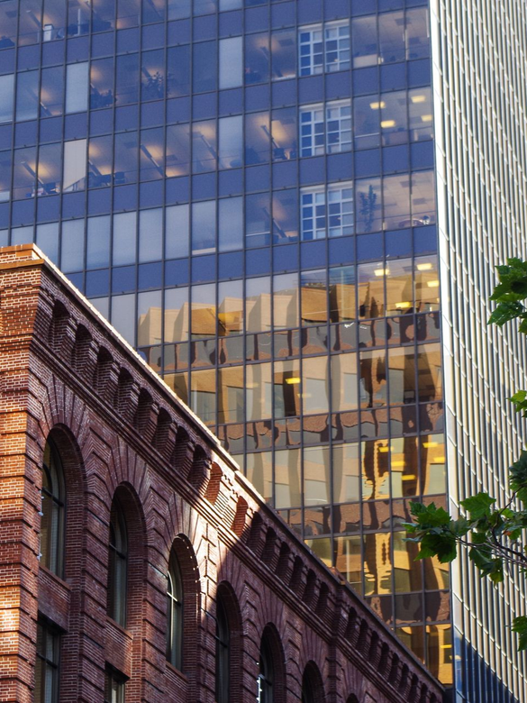Historic brick building in front of glass skyscraper with a U.S. flag flying above