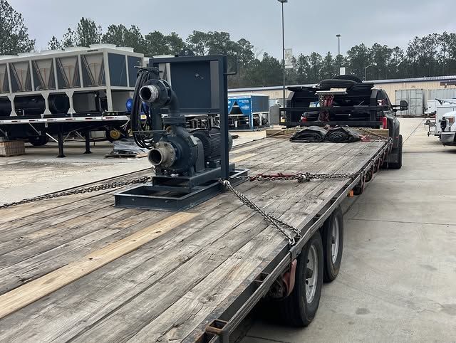 Flatbed trailer loaded with industrial equipment in a parking lot