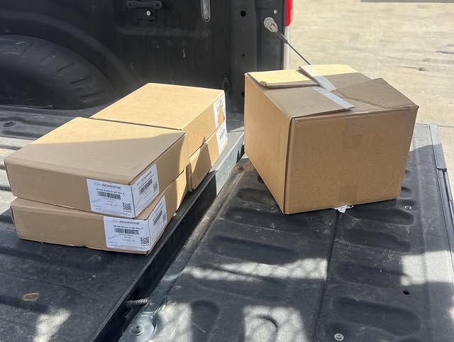 Cardboard shipping boxes on the open tailgate of a pickup truck in bright sunlight