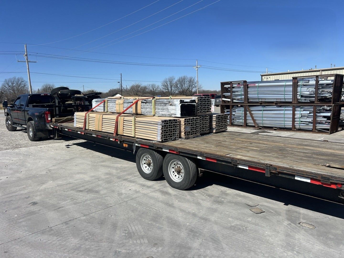Flatbed truck loaded with stacked materials in an industrial yard under a clear blue sky