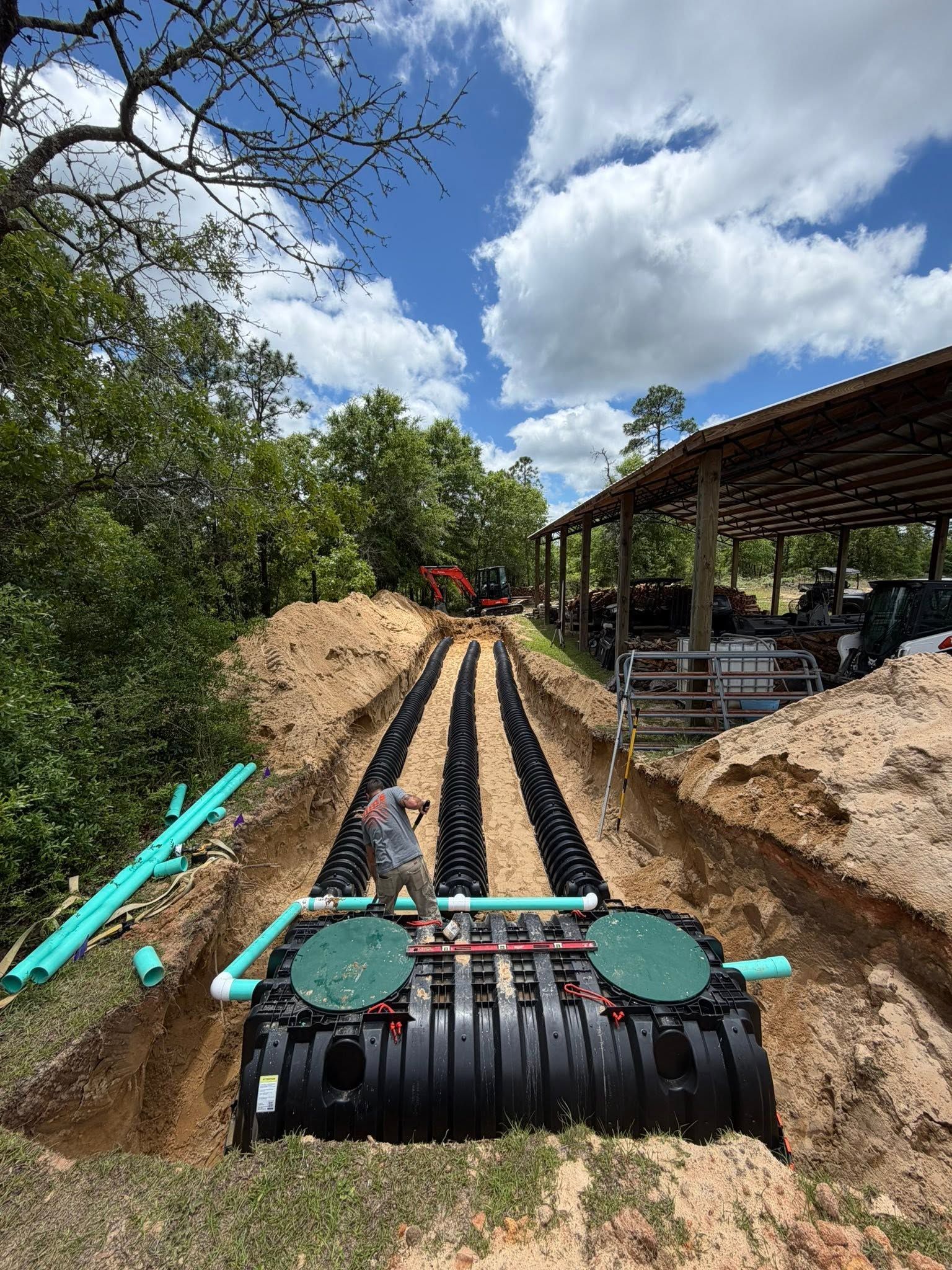 Rail-mounted train car on dirt tracks at an outdoor ride, with trees and a covered platform nearby.