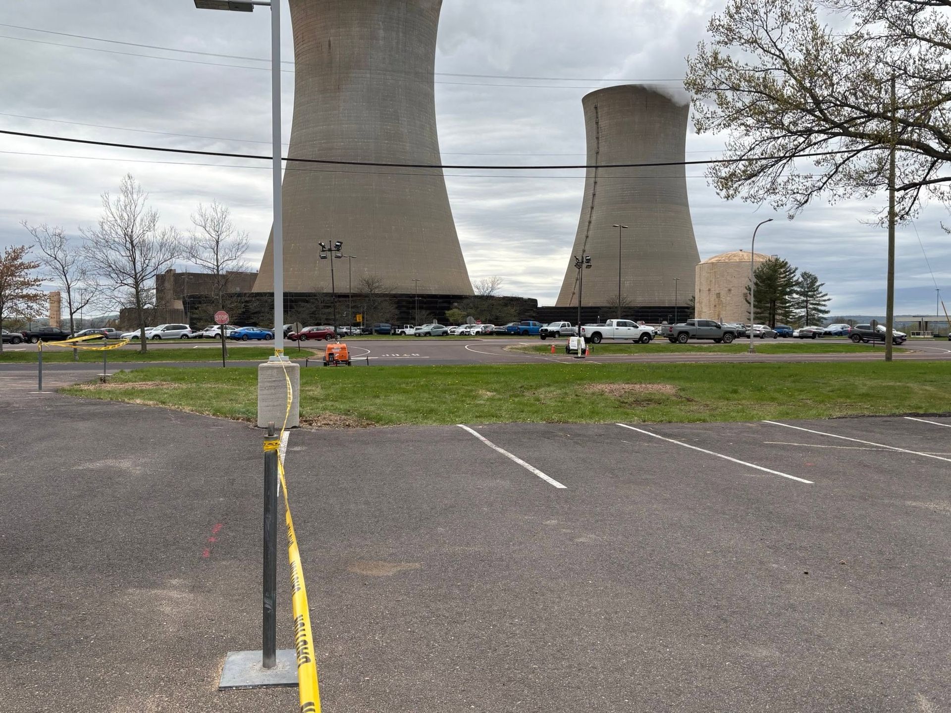 Empty parking lot with two large cooling towers under a cloudy sky