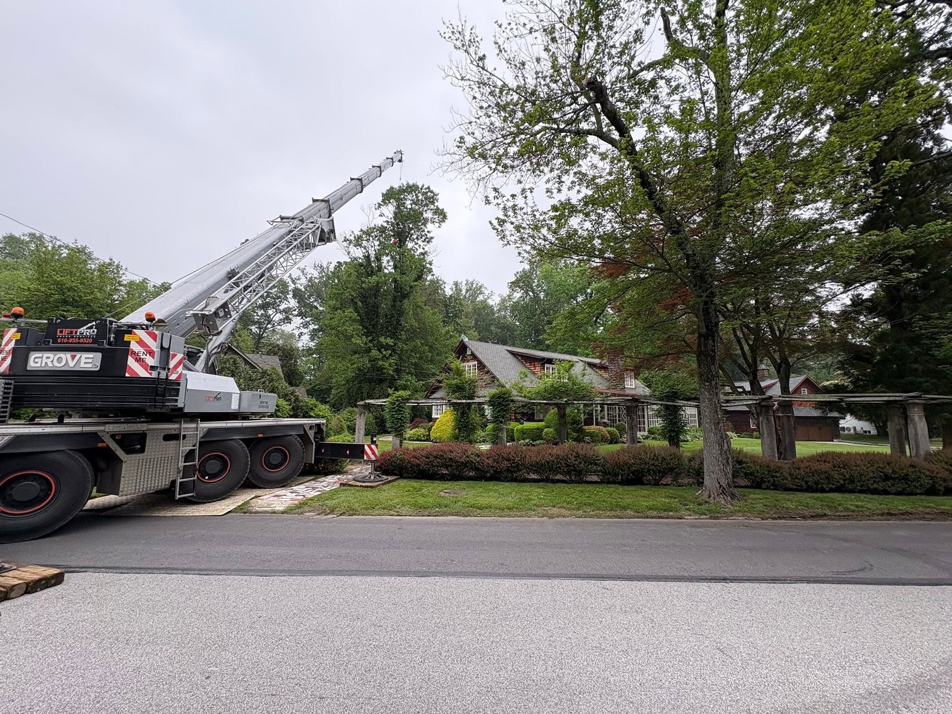 Tow truck lifting a crane in a tree-lined residential street after an авар?