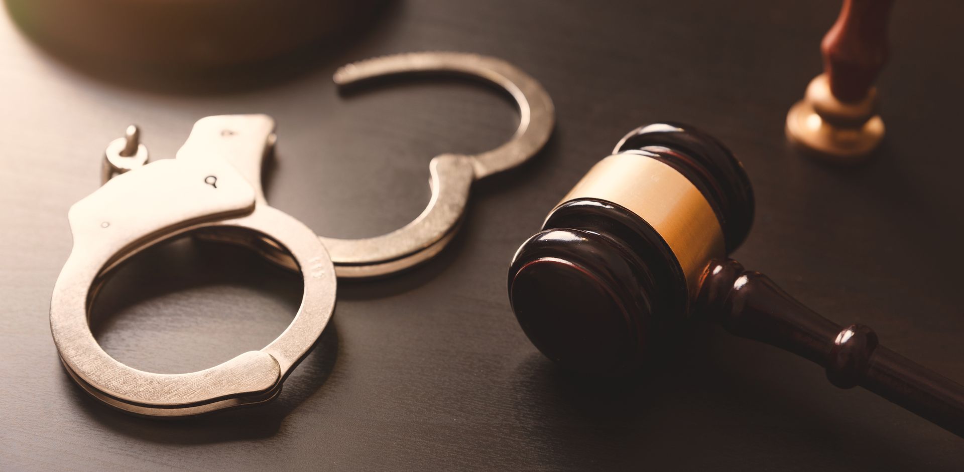 A pair of handcuffs and a judge 's gavel on a table.