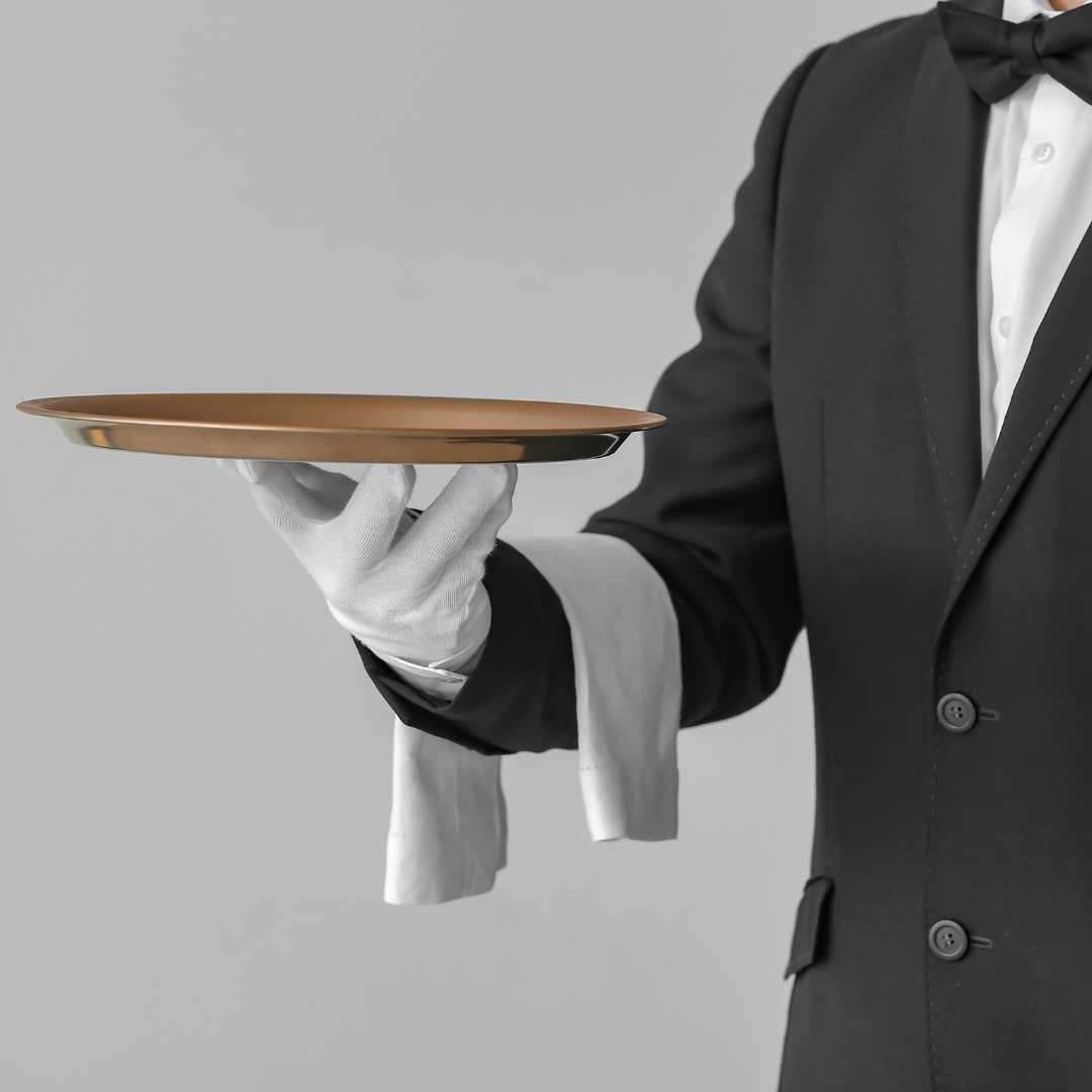 Butler in black suit and white gloves holding a tray.