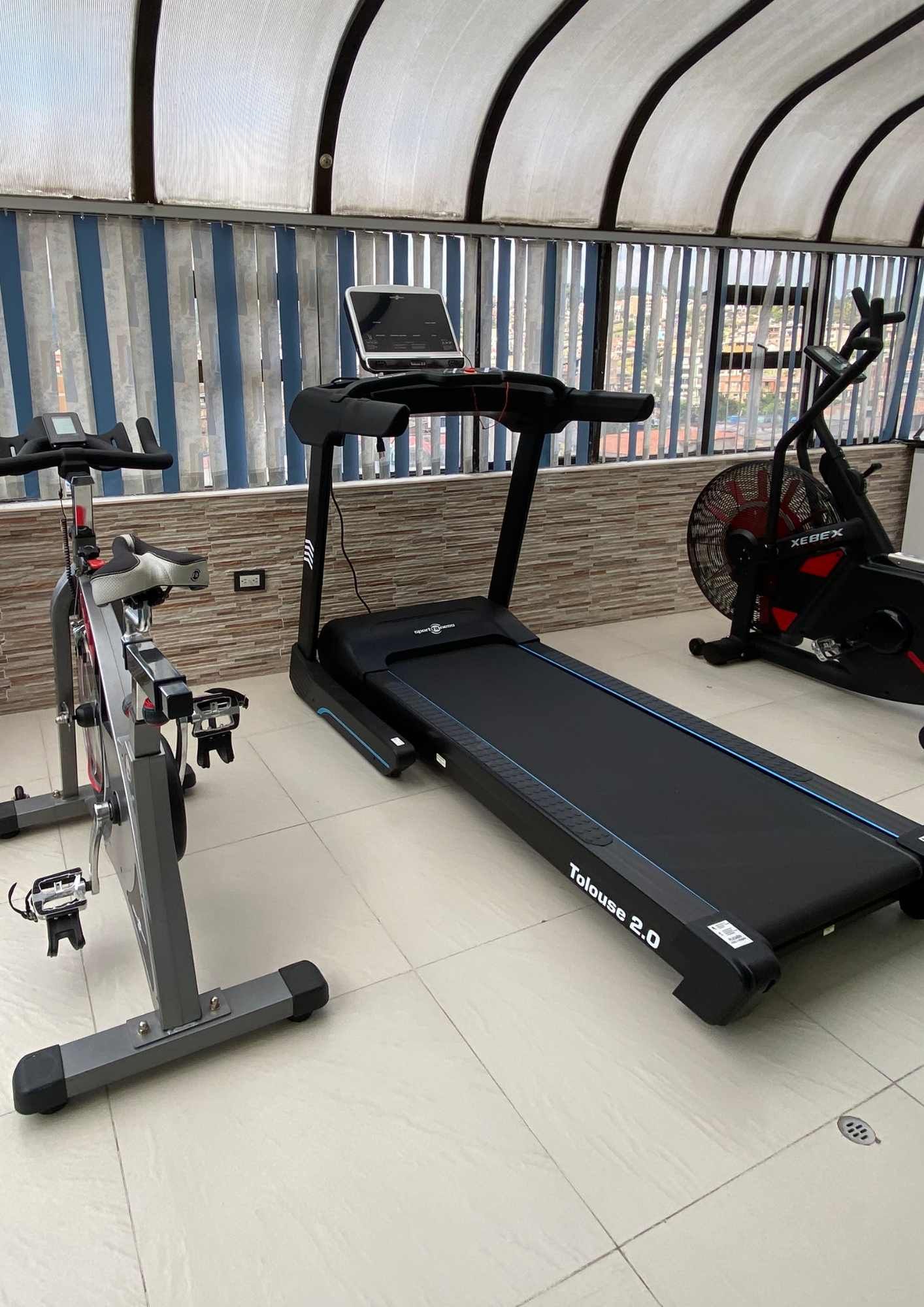 Treadmill, spin bike, and air bike in a well-lit gym.