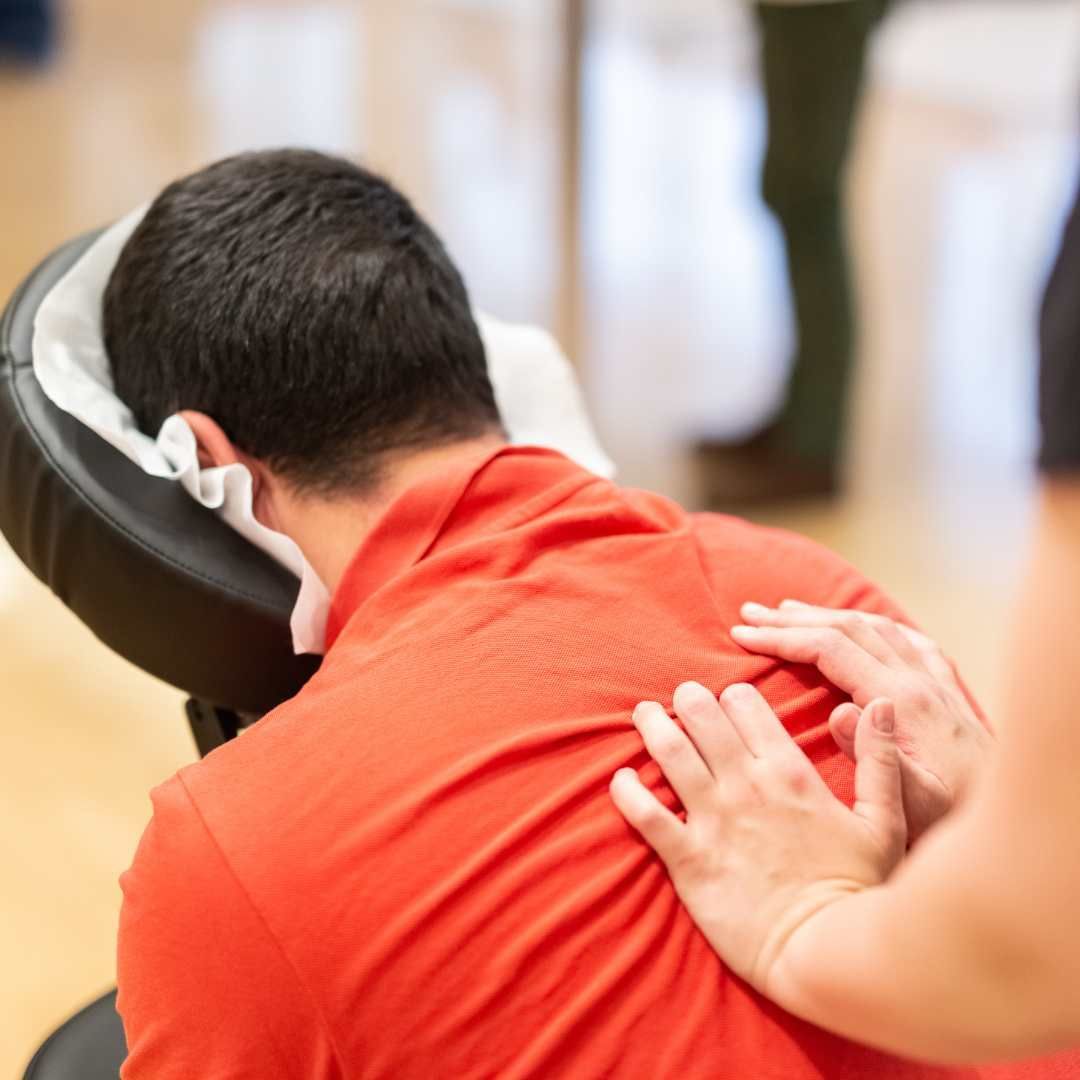 Person receiving a back massage. Hands on back. Red shirt.
