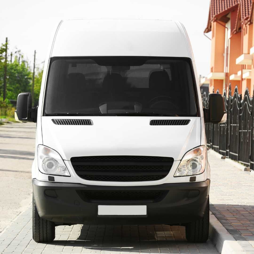 White cargo van parked on a brick street in front of a building.