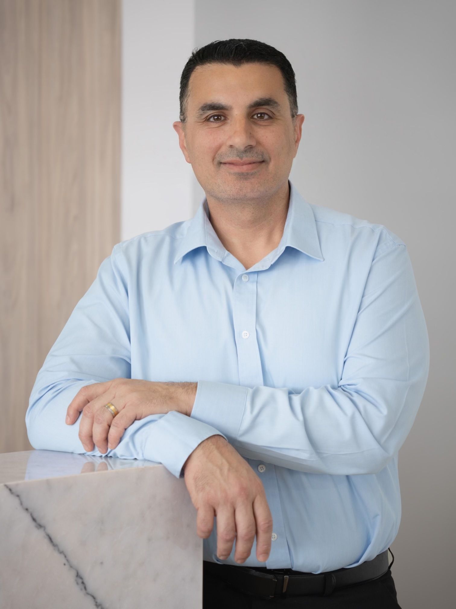 A man in a blue shirt is leaning on a counter.