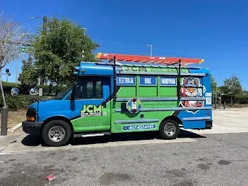 Blue and green bus with signs on the side parked outdoors under a clear sky