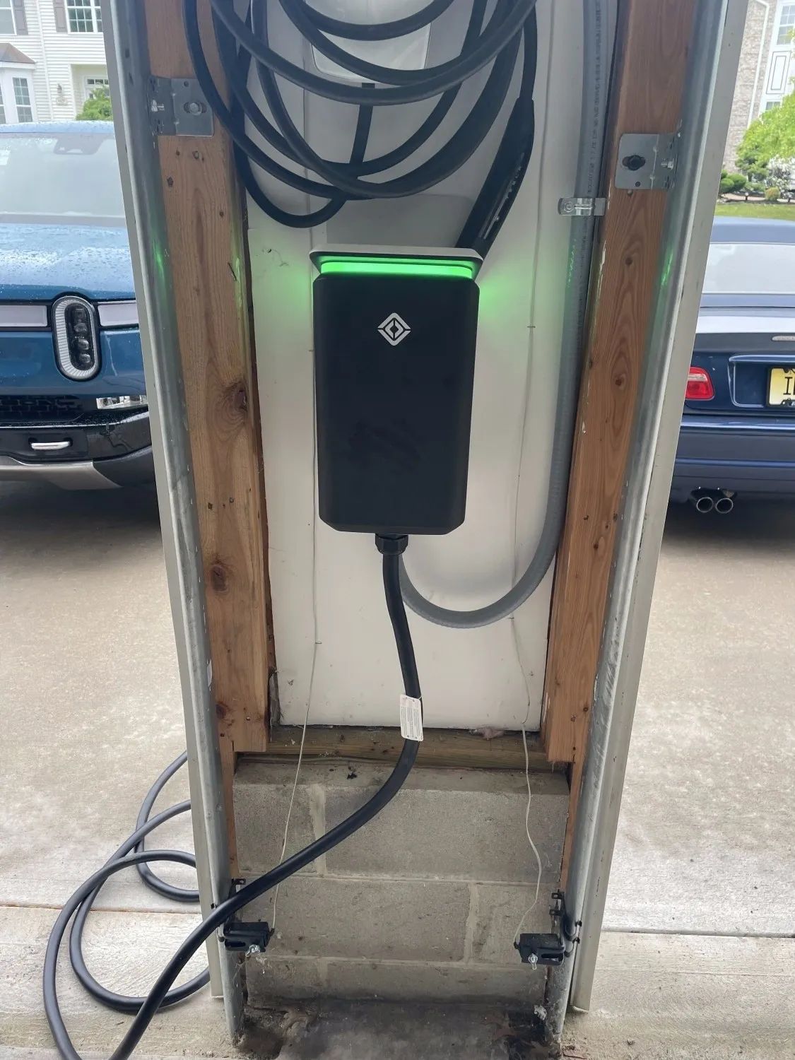 Electric vehicle charging station with black charger and coiled cable mounted in a narrow bay.