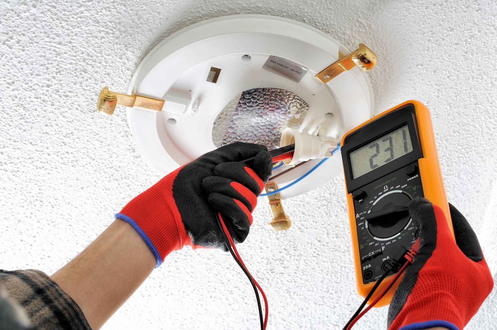 Residential hardwired smoke detector being replaced on a ceiling by an electrician for home safety.