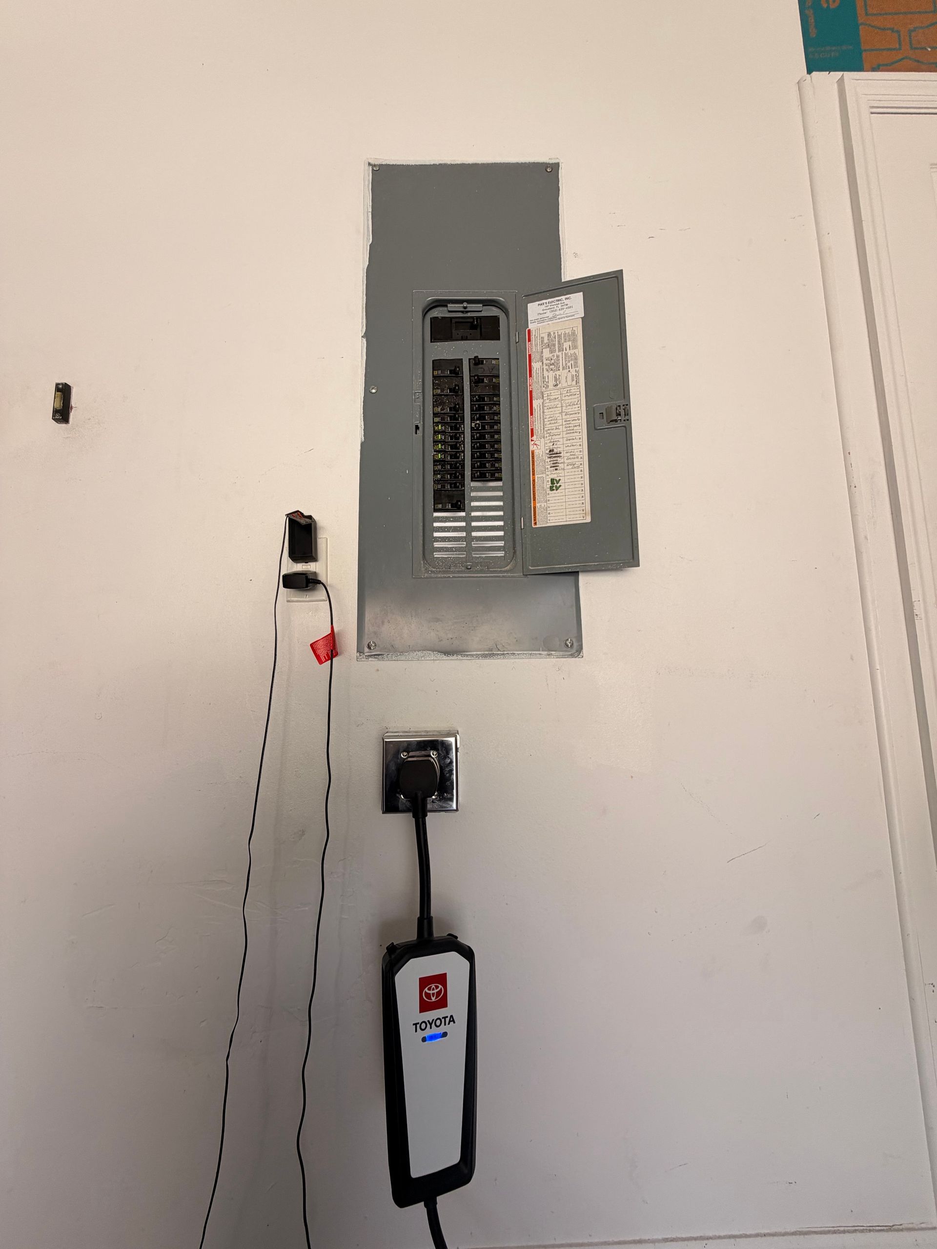 Garage electrical panel, charging outlet, and connected portable EV charger.