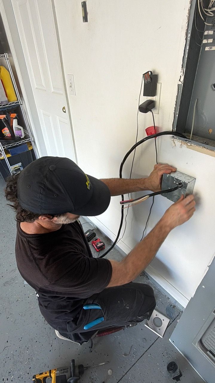 JCM Electric technician positioning the outlet box and wiring below the garage panel.