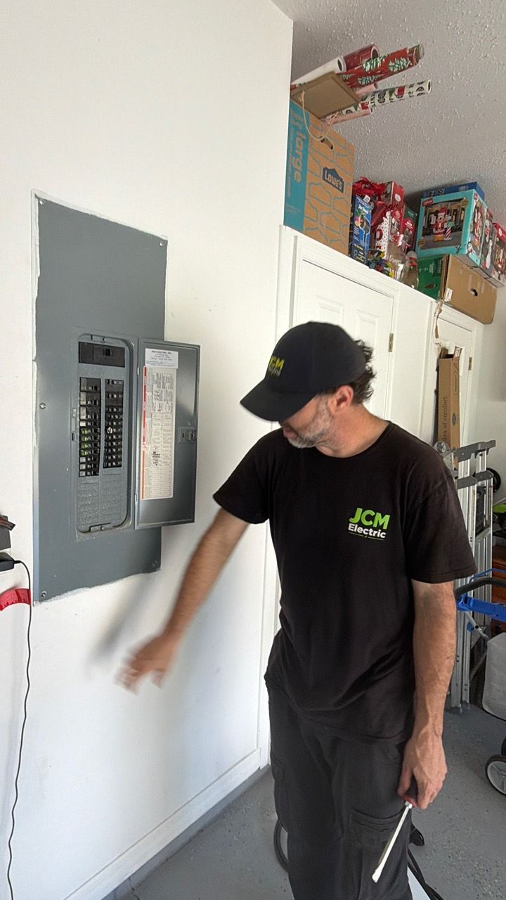 JCM Electric technician beside the garage electrical panel.