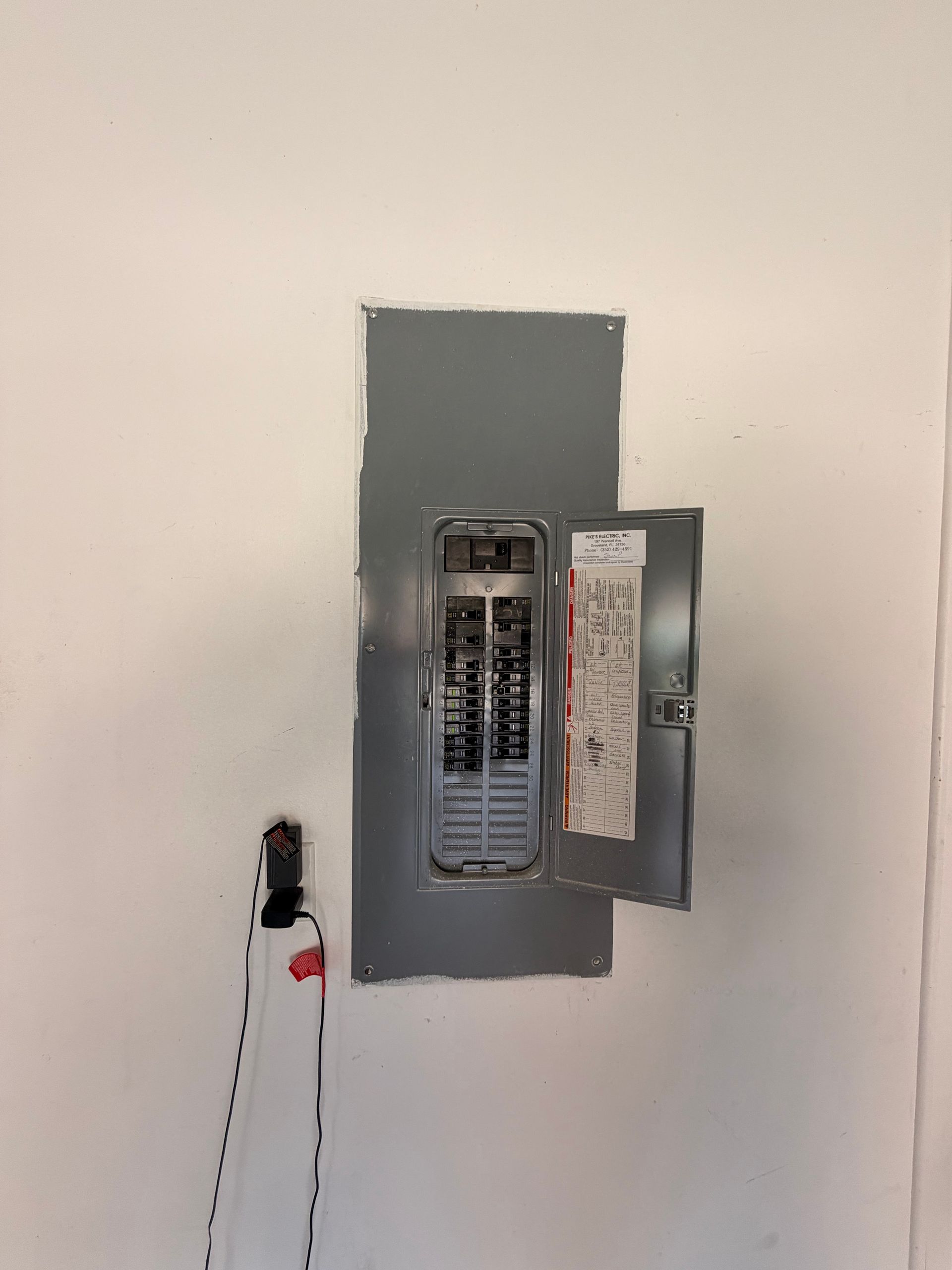 Garage electrical panel with its door open at the EV outlet installation site.