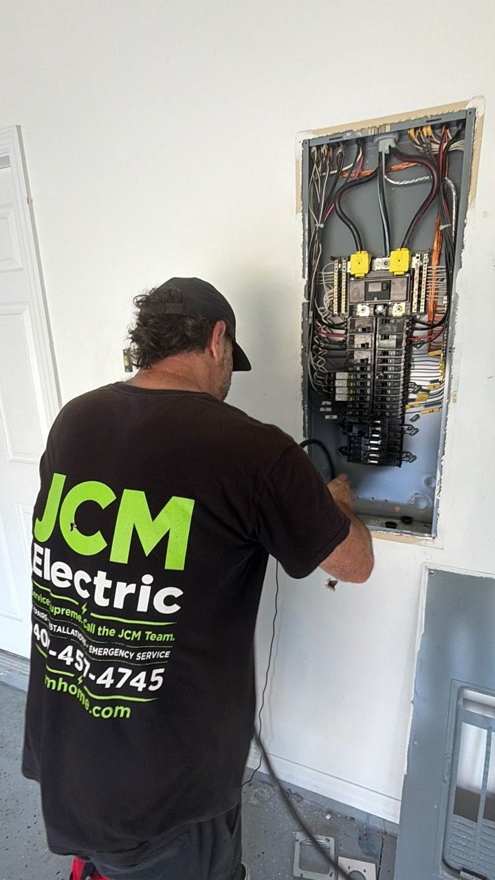 JCM Electric technician working at the open garage electrical panel.