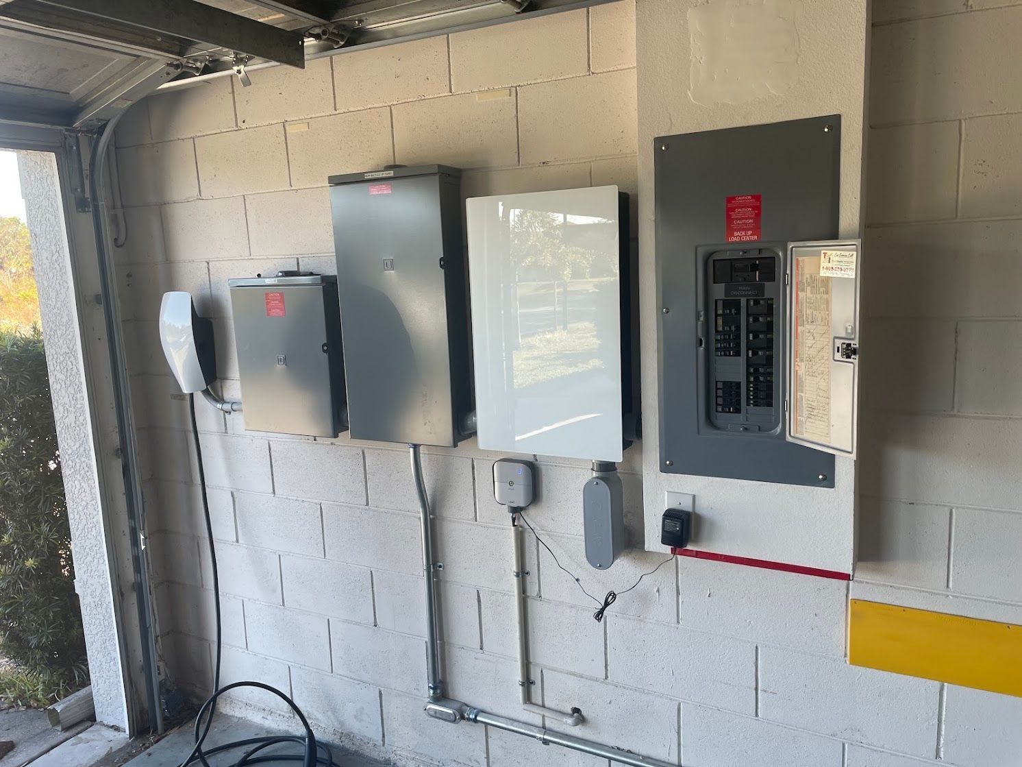 Residential electrical equipment with a breaker panel, EV charger and wall-mounted battery unit, from JCM Electric's project gallery