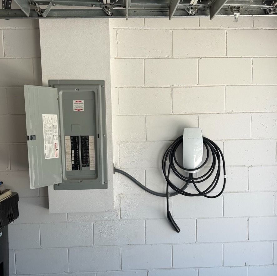 Wall-mounted EV charger beside a residential electrical panel.