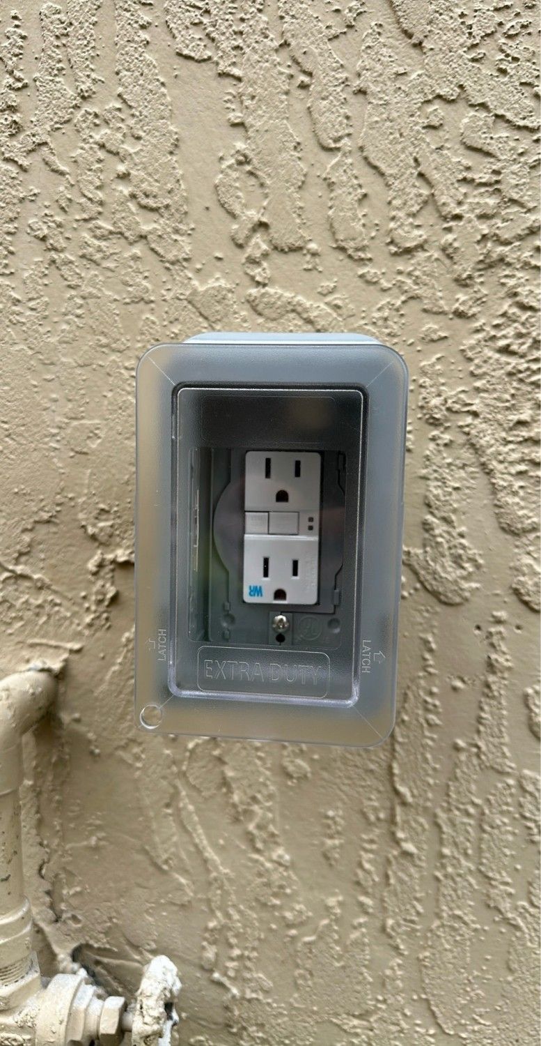 An outdoor GFCI outlet beneath a clear protective cover.